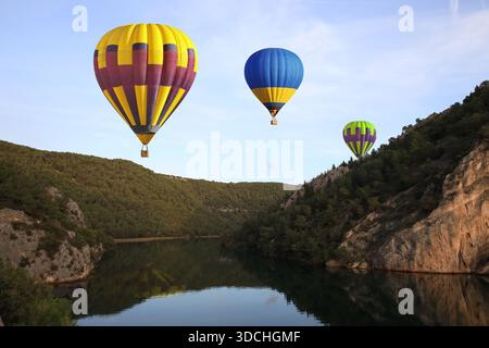 Montgolfières colorées volant au-dessus de la baie entre les rochers Banque D'Images