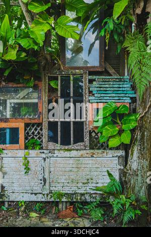 Une photo verticale d'un mur rustique et altéré avec des cadres de fenêtres en bois vintage empilés, des persiennes peintes pelées et fortement entrelacées avec de grandes Banque D'Images