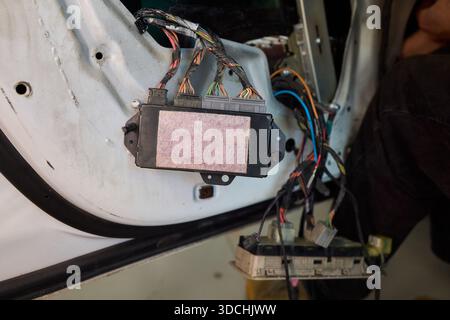 Une vue rapprochée détaillée des mains connectant divers fils dans un système électrique complexe de voitures Banque D'Images