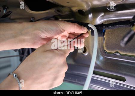 Une vue rapprochée détaillée des mains connectant divers fils dans un système électrique complexe de voitures Banque D'Images