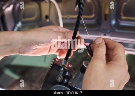 Une vue rapprochée détaillée des mains connectant divers fils dans un système électrique complexe de voitures Banque D'Images