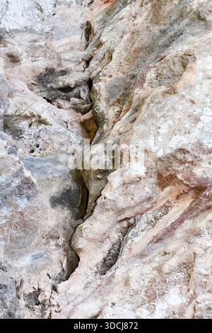 Plan vertical d'une paroi rocheuse de calcaire accidentée à Chypre, présentant des crevasses profondes, des textures altérées et des taches minérales naturelles. Banque D'Images