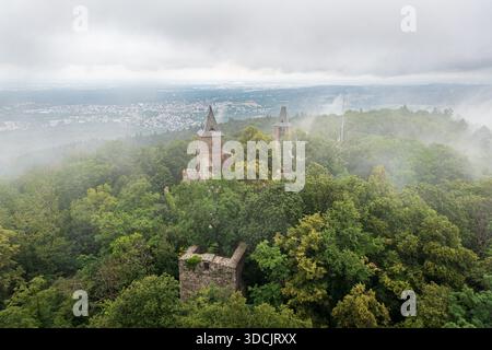 Vue aérienne du château de Burg Frankenstein entouré de brume, ses anciens murs de pierre et ses tours traversant la dense forêt verdoyante, Mühltal, Hesse, Banque D'Images
