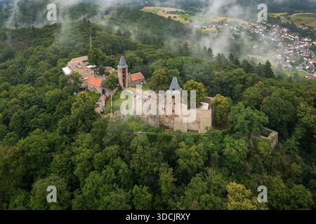 Vue aérienne de l'ancien château de Burg Frankenstein, ses murs de pierres altérées et ses tours perçant la dense canopée verte sous un ciel brumeux, Mühltal, Banque D'Images