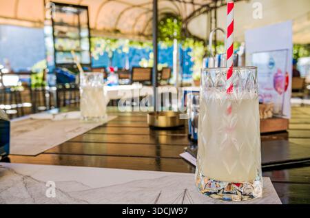 Une boisson rafraîchissante à la limonade dans un verre avec une paille rayée rouge et blanche. Banque D'Images