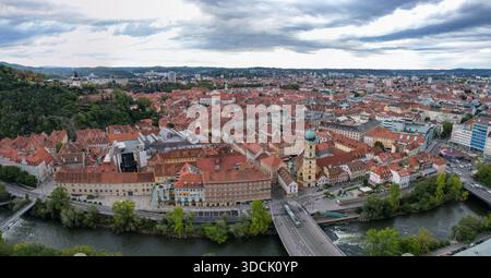Vue aérienne des toits en terre cuite en cascade vers la rivière mur, dominée par la tour de l'horloge, Graz, Styrie, Autriche. Banque D'Images