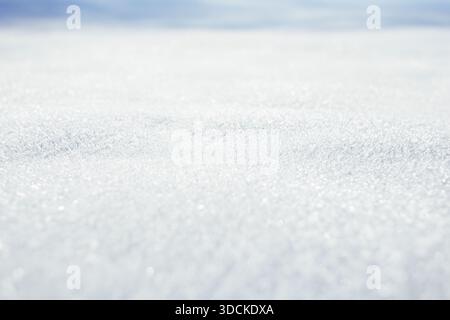 Gros plan de la neige mousseuse et granuleuse ou de la texture givrée. La faible profondeur de champ crée un fond d'hiver lumineux, pur et propre avec des tons bleus doux Banque D'Images