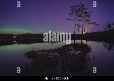 Aurora Borealis sur une petite île dans un lac calme la nuit, Finlande Banque D'Images