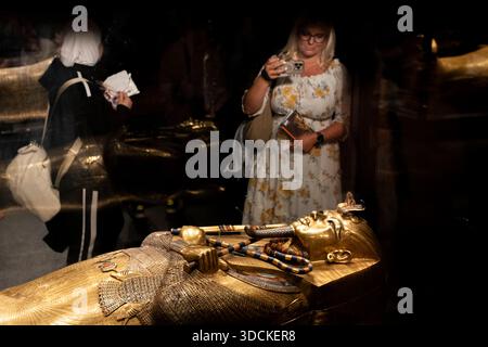 (251221) -- GIZEH, Dec. 21, 2025 (Xinhua) -- les gens voient le Coffin intérieur en or massif de Toutankhamon dans la salle d'exposition du Roi Toutankhamon du Grand Musée égyptien de Gizeh, Egypte, le 20 Dec. 2025. Le Grand Musée égyptien (GEM) a ouvert ses portes au public le 4 novembre, s'établissant comme l'une des plus grandes expositions au monde de reliques anciennes, et un fort high-tech dédié à la conservation du patrimoine. Les galeries principales exposent pour la première fois des milliers d'antiquités précédemment entreposées, abritant la collection complète de quelque 5 992 artefacts de la tombe du garçon-roi Toutankhamon. Banque D'Images