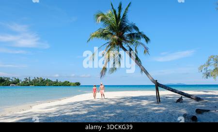 Profitez d'une belle journée sur l'île de Koh Kood que deux visiteurs prennent une promenade tranquille sur le sable doux sous les palmiers oscillants, entourés par des eaux bleues claires et un ciel vibrant de Thaïlande || modèle libéré Banque D'Images