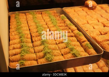 Morceaux de baklava roulés recouverts de pistache disposés dans un plateau métallique dans une pâtisserie en Bosnie-Herzégovine. Concept de dessert traditionnel. Banque D'Images