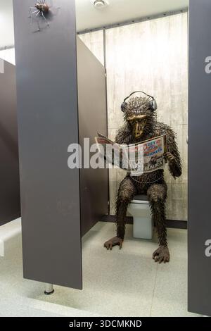 Sculpture originale grandeur nature représentant un singe assis sur les toilettes, lisant un journal dans les toilettes des hommes du British Ironworks Centre Banque D'Images
