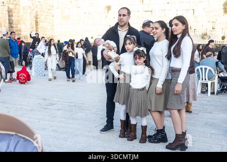 Jérusalem, Israël, le 22 décembre 2025, Une famille juive religieuse avec quatre enfants posant pour une photo devant les blocs de calcaire du mur Occidental Banque D'Images