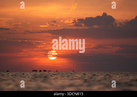 Voyage roumanie tulcea sulina danube delta mer noire soleil plongeant au-dessous de l'horizon, peignant le ciel de la mer noire orange et rouge avec des bateaux lointains Banque D'Images