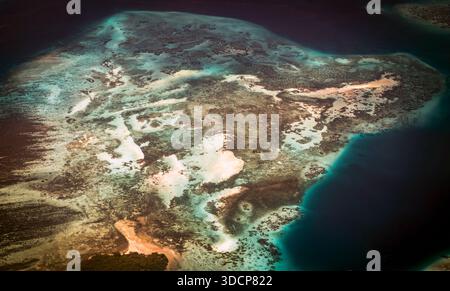 Vue aérienne d'une île tropicale entourée d'eaux turquoises, mettant en valeur les récifs coralliens et les plages de sable Banque D'Images