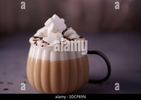 boisson chaude confortable dans une tasse texturée surmontée de guimauves moelleuses et de saupoudrées de chocolat sur fond de lavande tamisée pour une chaleur invitante et comfo Banque D'Images