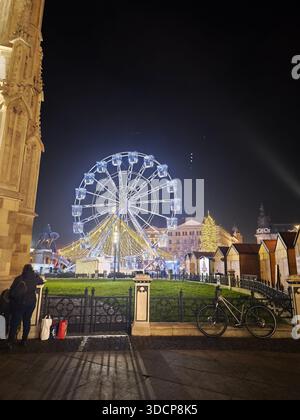 Grande roue dans le centre-ville de Cluj-Napoca la nuit, illuminée par des lumières d'hiver festives, ambiance de marché de Noël Banque D'Images