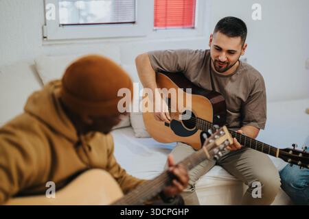 Deux amis jouent de la guitare acoustique ensemble dans un cadre confortable de salon et partagent de la musique Banque D'Images