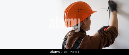 architecte dans le mur de mesure de casque dur utilisant la règle en acier. architecture et concept de rénovation de la maison. bannière. copier l'espace Banque D'Images