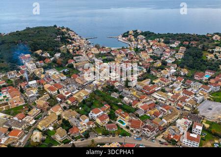 Photo aérienne détaillée du centre-ville de Kassiopi par drone montrant une architecture dense, l'entrée principale du port et la végétation verdoyante entourant le complexe i. Banque D'Images