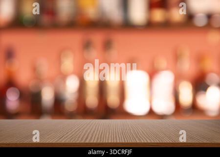 Vider le comptoir de bar en bois et les bouteilles floues sur les étagères. Espace pour le design Banque D'Images