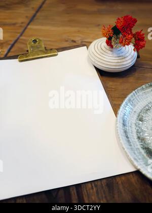Un papier blanc vierge sur une planche à pince en bois, servant une maquette pour le menu du restaurant ou l'affichage d'art. Le presse-papiers est placé sur une table en bois rustique à côté de sma Banque D'Images