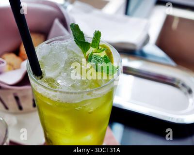Une boisson verte jaune froide servie dans un grand verre. Ressemble à un thé vert citron glacé au miel, mojito vierge, ou soda aux agrumes, est emballé avec du Clea cristal Banque D'Images