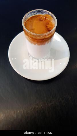 Café sale tendance servi dans un gobelet en verre transparent. Les boissons de spécialité comprennent une dose d'espresso chaude et robuste versée délicatement sur du lait ou de la crème glacée Banque D'Images