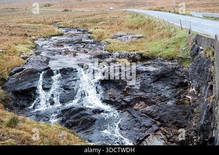 ruisseau descendant les rochers à la route régionale r336 teernakill sud à travers les montagnes du connemara et pont à travers le comté de rivière galway république de Banque D'Images
