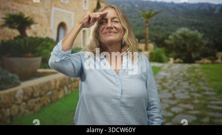 Femme âgée pointe le doigt vers le temple avec la main visible devant une cour de bâtiment en pierre ; confiance résilience sagesse. Banque D'Images