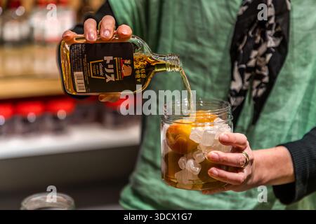 Personne versant du whisky Suntory dans un verre contenant des prunes ressemblant à des abricots à Tanabe pour faire de la liqueur de prunes umeshu (梅酒)., préfecture de Wakayama, Japon Banque D'Images