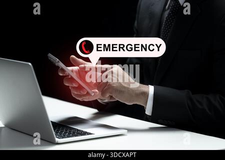 Homme d'affaires est représenté à l'aide d'un smartphone, avec une notification d'alerte signalant un appel d'urgence. Un ordinateur portable est vu près de sa main. La nature urgente Banque D'Images