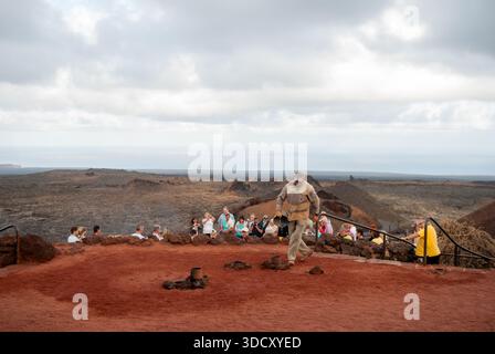 Groupe de touristes attendant le guide pour montrer le jet de vapeur créé en versant de l'eau dans des trous dans le sol, Timanfaya National Park, Lanzarote Banque D'Images
