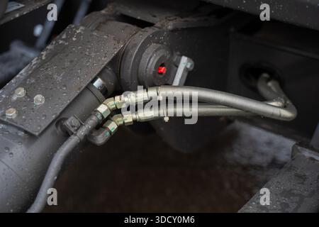 Détail du système hydraulique de pelle industrielle comprenant des flexibles, des accouplements métalliques et une surface humide, axé sur la reliab d'ingénierie d'équipement lourd Banque D'Images