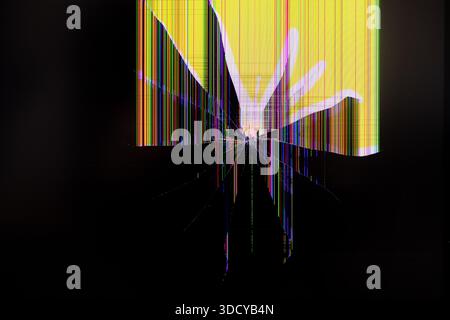 Gros plan d'un écran numérique endommagé montrant des lignes verticales colorées brillantes et rayonnant des fissures brisées par l'impact, représentant un appareil électronique f Banque D'Images