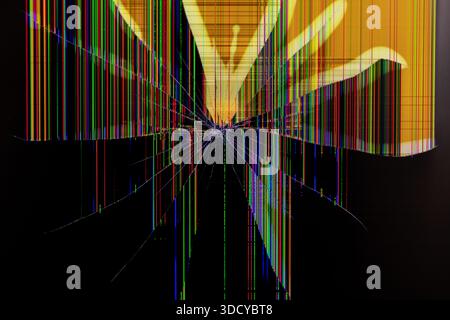 Gros plan d'un écran numérique gravement cassé avec des lignes verticales colorées vibrantes et des motifs de fissure rayonnants, soulignant la panne technologique an Banque D'Images