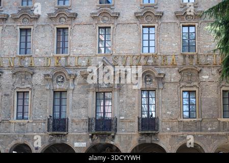 LUGANO, SUISSE, 06.20.2025 :Une façade de banque italienne historique présente des pierres altérées, des frontaux décoratifs et des balcons en fer forgé. Texte ensoleillé Banque D'Images