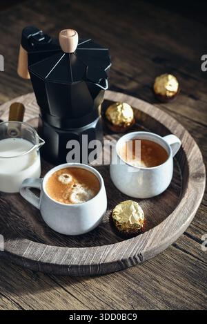 Cafetière moka noir avec poignée en bois et deux tasses de café sur plateau en bois Banque D'Images