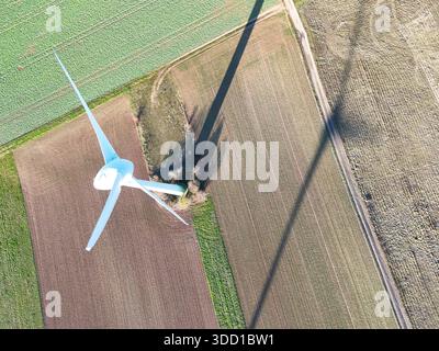 La turbine éolienne aérienne projette de l'ombre sur les champs agricoles Banque D'Images