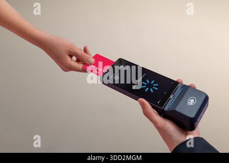 Le client insère une carte de paiement dans un terminal de point de vente mobile, illustrant le processus de paiement, la transaction au détail et l'expérience moderne de paiement par carte sans espèces Banque D'Images