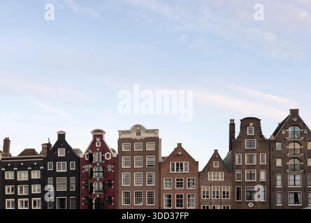 Maisons colorées en bord de mer du canal Damrak, façades hollandaises classiques, destination de voyage célèbre. Pour les guides touristiques, les visuels de blog de voyage et les médias sociaux po Banque D'Images