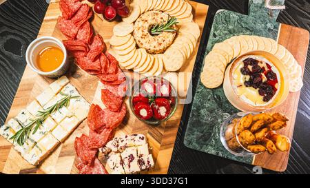Belle planche de charcuterie avec salami, raisins, craquelins, assortiment de fromages, camembert cuit au four avec sauce aux fruits, fromage à la crème, poivrons farcis et miel Banque D'Images