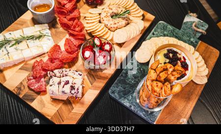 Belle planche de charcuterie avec salami, raisins, craquelins, assortiment de fromages, camembert cuit au four avec sauce aux fruits, fromage à la crème, poivrons farcis et miel Banque D'Images