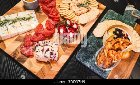Belle planche de charcuterie avec salami, raisins, craquelins, assortiment de fromages, camembert cuit au four avec sauce aux fruits, fromage à la crème, poivrons farcis et miel Banque D'Images