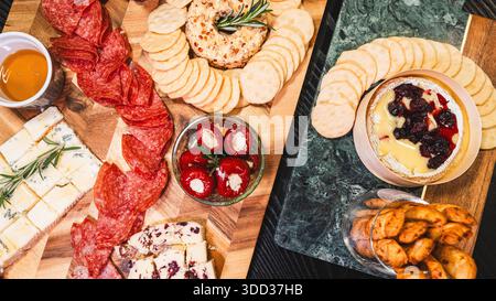 Belle planche de charcuterie avec salami, raisins, craquelins, assortiment de fromages, camembert cuit au four avec sauce aux fruits, fromage à la crème, poivrons farcis et miel Banque D'Images