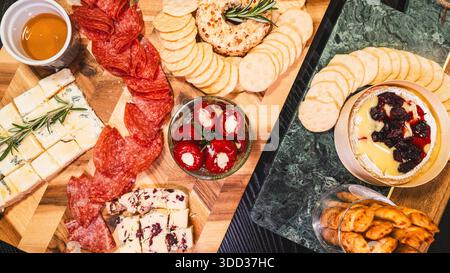 Belle planche de charcuterie avec salami, raisins, craquelins, assortiment de fromages, camembert cuit au four avec sauce aux fruits, fromage à la crème, poivrons farcis et miel Banque D'Images