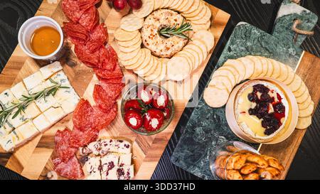 Belle planche de charcuterie avec salami, raisins, craquelins, assortiment de fromages, camembert cuit au four avec sauce aux fruits, fromage à la crème, poivrons farcis et miel Banque D'Images
