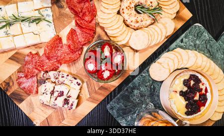 Belle planche de charcuterie avec salami, raisins, craquelins, assortiment de fromages, camembert cuit au four avec sauce aux fruits, fromage à la crème, poivrons farcis et miel Banque D'Images