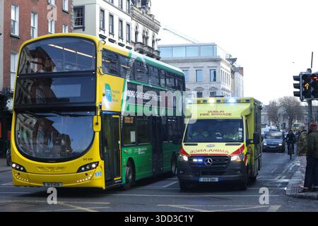 Dublin, Irlande - 24 décembre 2025 - une ambulance avec des lumières clignotantes passe devant un bus tout en répondant à un appel d'urgence dans la ville de Dublin représentant des scènes de rue dans la capitale irlandaise la veille de Noël Banque D'Images