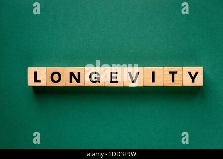Le mot longévité écrit sur des blocs de bois. Le concept de longévité. Habitudes alimentaires, attitude positive, relations sociales et activité physique. Banque D'Images